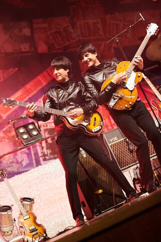Zwei Beatles mit Gitarren auf vorderer Seite von Bühne