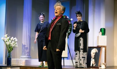 Zwei Frauen im Hintergrund ein Mann im Vordergrund in einer Trauerfeier Szene, führt zum Kalendereintrag